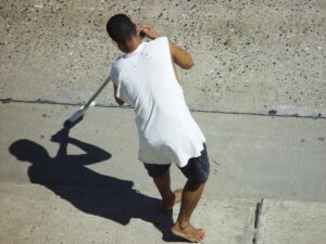 African American male sweeping sidewalk.