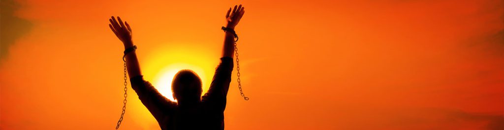 person in front of sunset breaking chains with addiction hypnosis and hypnotherapy.