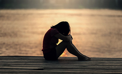 Sad girl sitting on dock by water, featured image by Sasin Tipchai from Pixabay