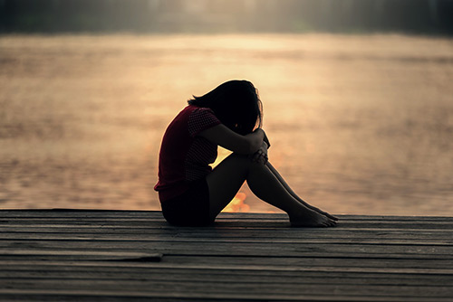 Sad girl sitting by water, image by Sasin Tipchai from Pixabay