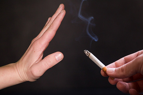 hand help up in front of cigarette, hypnosis to quit smoking, vaping or chewing tobacco, image by Tumisu from Pixabay.